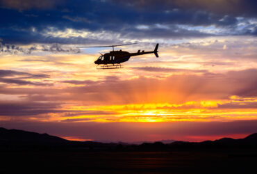 Bell 206 helicopter in flight at sunset